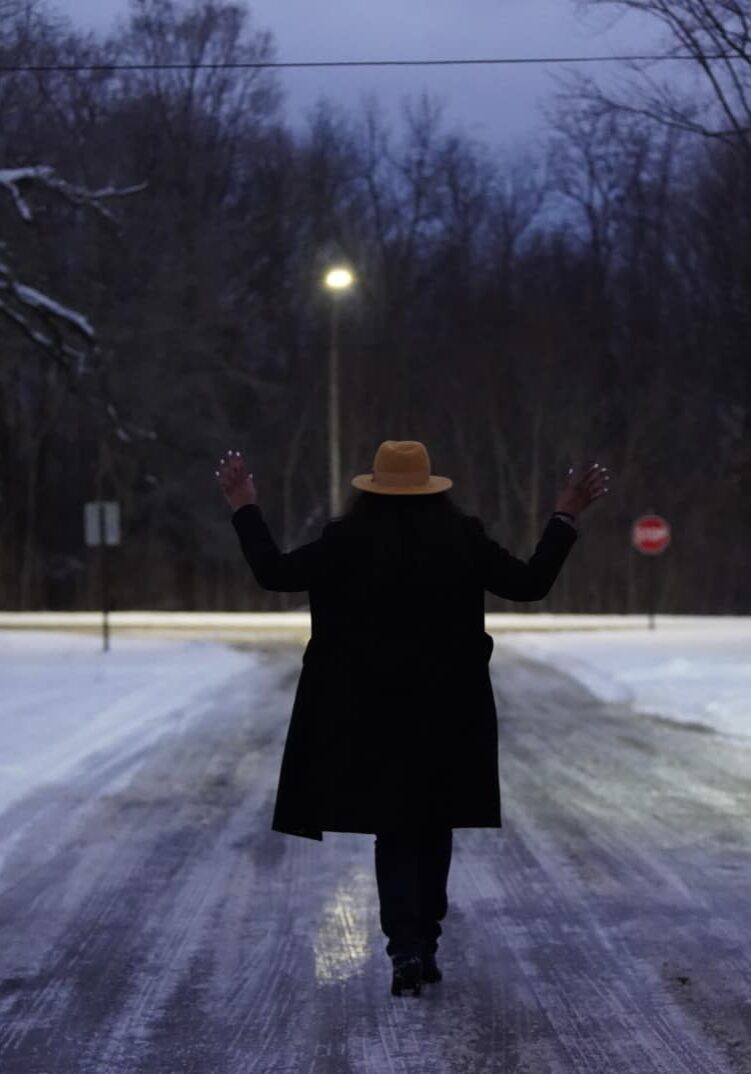 Ronnika walking down an icy road in Michigan at night.