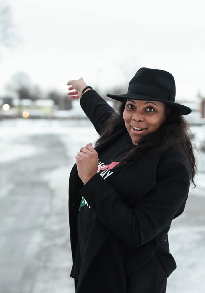 Ronnika pointing to a house in the winter.